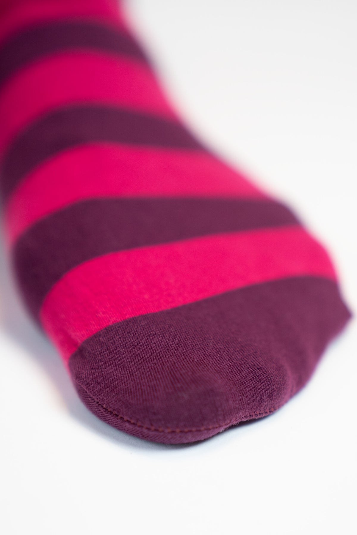 Nahaufnahme der Fussspitze der Strumpfhose mit flacher Naht und Ringelmuster in Pink und Dunkelviolett.