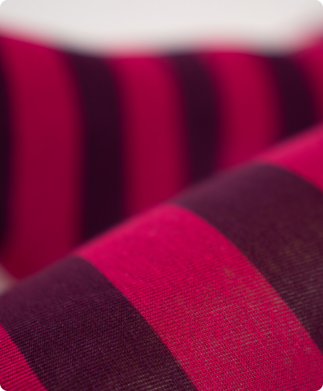 Nahaufnahme des gestrickten Ringel-Musters in Pink und Dunkelviolett aus Bio-Baumwolle, Detailaufnahme der Strickstruktur.